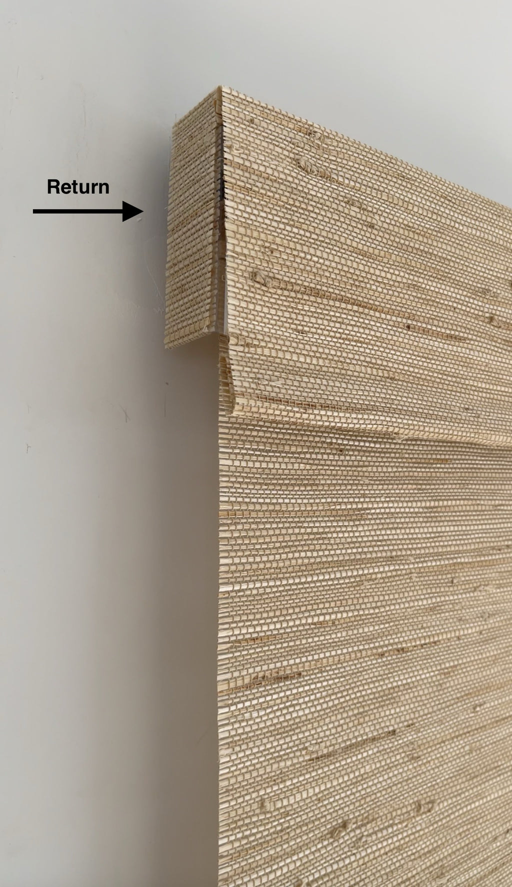 Luxury custom Roman shades in bedroom with natural bamboo texture and tailored flat fold