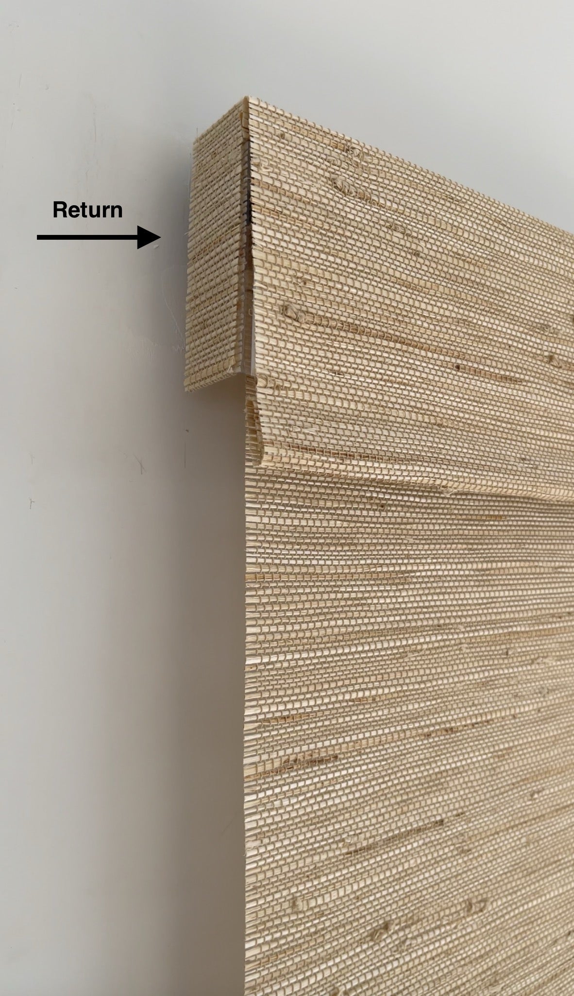 Luxury custom Roman shades in bedroom with natural bamboo texture and tailored flat fold